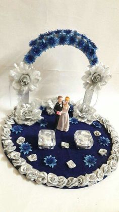 a wedding cake with blue and white frosting on it, surrounded by roses and crystal cubes