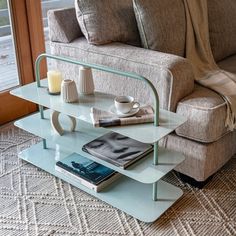 a living room with a couch, coffee table and book on the floor in front of a window