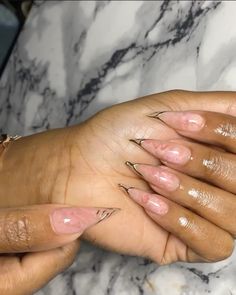 a woman's hands with pink and gold nail polish on her nails, while she is holding the other hand