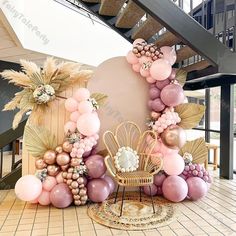 a balloon arch with balloons and flowers on the floor in front of a stair case