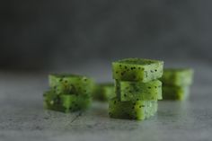 three pieces of green food sitting on top of a counter next to each other with tiny black dots all over them