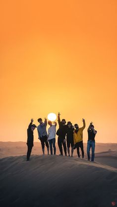 a group of people standing on top of a sand dune under a yellow and orange sky