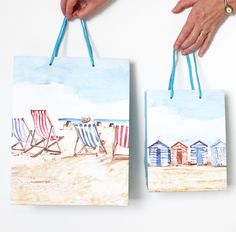 two bags with beach chairs on them are being held by someone's hands