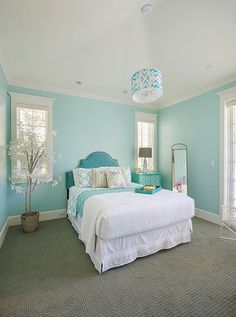 a bed room with a neatly made bed next to a window and a mirror on the wall