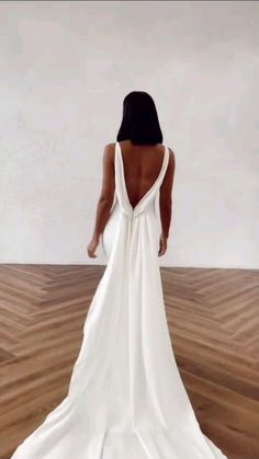 a woman in a white dress is standing on a wooden floor with her back to the camera