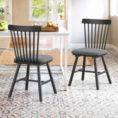 two black chairs sitting next to each other on a kitchen floor with an area rug