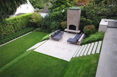 an outdoor fireplace and seating area in the middle of a lawn with steps leading up to it