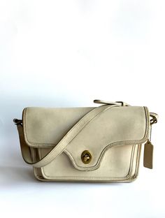 This vintage Coach Kent bag, dating back to 1993, is crafted in the classic bone color. The bag shows its age with some color wear at the corners and discoloration throughout, including on the strap. Despite this, the interior and the area under the flap remain very clean, highlighting its original vintage condition. A timeless piece for any Coach collector or vintage fashion enthusiast. Current style number 9916 Brass turnlock closure. Full-length outside back pocket. Full-length front gusseted pocket under leather-lined flap. Full-length inside zipper pocket. 48" Adjustable shoulder strap. 10" X 6" X 3" Butterscotch shown. Black, Bone, Bordeaux, Bottle Green, British Tan, Mahogany, Navy, Red, Stone. Classic Cream Flap Bag For Everyday, Vintage Satchel Flap Bag For Formal Occasions, Vintage Shoulder Flap Bag, Vintage Crossbody Flap Bag For Formal Occasions, Vintage Crossbody Flap Bag For Formal Events, Vintage Flap Bag With Detachable Strap For Formal Occasions, Formal Cream Crossbody Flap Bag, Vintage Leather Flap Bag For Formal Occasions, Classic Beige Satchel With Leather Lining