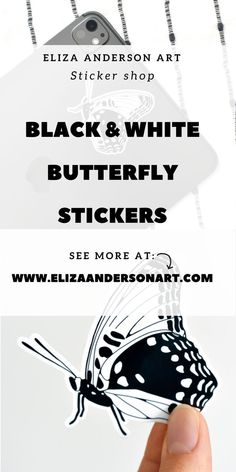 the black and white butterfly sticker is being held up by a person's hand