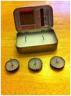 an open tin with three candles in it on top of a wooden table next to other items