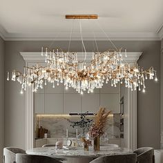 a chandelier hanging from the ceiling in a dining room with chairs and table