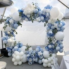 a blue and white balloon arch decorated with greenery