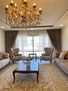 a living room filled with furniture and a chandelier hanging from the ceiling in front of a window