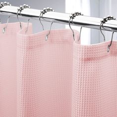 a pink shower curtain hanging from a metal rod