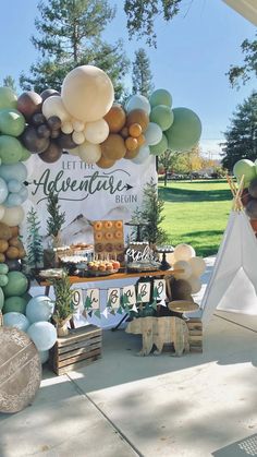 an outdoor dessert table with balloons and decorations on the outside, along with a teepee tent