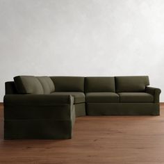 a large green couch sitting on top of a wooden floor next to a white wall