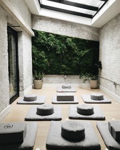 a yoga room with lots of pillows on the floor and plants growing in the wall