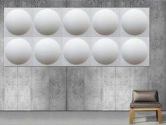 a chair sitting in front of a large wall with white balls hanging from it's sides