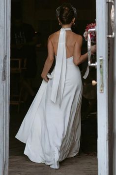 a woman in a white dress is walking out the door