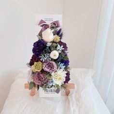 a bouquet of flowers is sitting on top of a chair with a card in the background