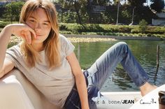 a woman sitting on the edge of a boat in front of a body of water