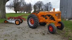 an orange tractor parked next to a tree