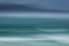 an ocean scene with waves and mountains in the background