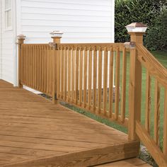 a wooden deck with railing and lights on the side of it in front of a white house