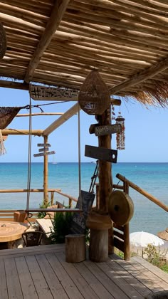 a wooden deck next to the ocean under a thatched roof