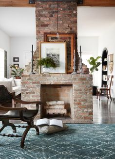 a living room with a brick fireplace and pictures hanging on the wall over it's mantle