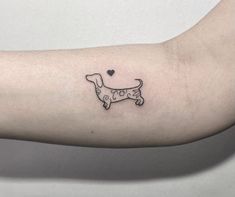 a small black and white dog tattoo on the left arm with a heart in it