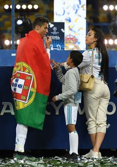 a group of people standing on top of a soccer field next to a giant flag