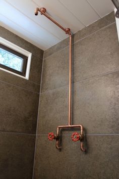 a bathroom with a shower head, window and tiled wall in it's corner