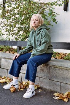 a woman sitting on a bench with her legs crossed Green Hoodie With Adjustable Hood For Streetwear, Green Hoodie With Ribbed Cuffs For Streetwear, Khaki Hoodie Sweatshirt For Streetwear, Green Double-lined Hoodie For Streetwear, Khaki Hoodie For Winter Streetwear, Winter Khaki Hoodie For Streetwear, Green Urban Hoodie With Kangaroo Pocket, Urban Green Hoodie With Kangaroo Pocket, Green Sweatshirt With Kangaroo Pocket For Streetwear