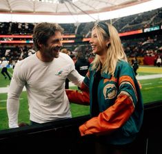 a man and woman standing next to each other at a football game