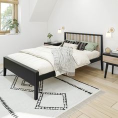 a bed sitting on top of a wooden floor next to a white and black rug