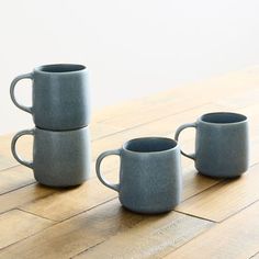 three grey cups sitting on top of a wooden table