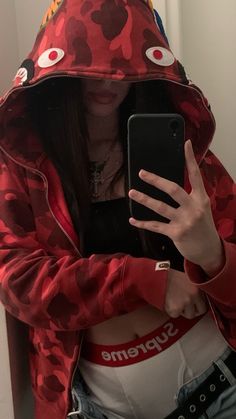 a woman wearing a red hoodie and holding a cell phone in her right hand