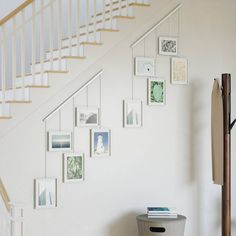 a white staircase with pictures on the wall and a trash can under it next to a stair case