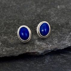 Lapis lazuli stud earrings with a sterling silver double bezel setting and post fitting.  Lapis lazuli is an alternative birthstone for the month of September.  Dimensions (approx): * Length: 1cm  * Width: 0.8cm  * Lapis lazuli stone: 6mm x 8mm  Materials: * Sterling Silver * Lapis Lazuli Beyond Biasa creates unique jewellery that is inspired by antique and tribal designs from around the globe. All of our pieces are handmade so please allow for slight variations in size and colour. Sterling Silver Sapphire Gemstone Earrings, Sapphire Color Oval Sterling Silver Earrings, Sterling Silver Sapphire Birthstone Earrings, Sapphire Oval Sterling Silver Earrings, Oval Sapphire Earrings In Sterling Silver, Oval Sapphire Sterling Silver Earrings, Sterling Silver Cabochon Earrings Gift, Classic Sterling Silver Birthstone Earrings, Blue Cabochon Sterling Silver Earrings