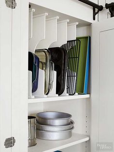 an organized kitchen cupboard with pots and pans