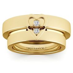 two gold wedding bands with diamonds in the center and heart on each band, set against a white background