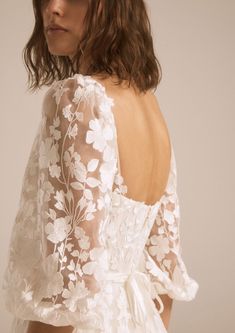 the back of a woman's wedding dress with white flowers and leaves on it