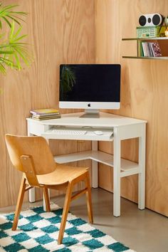 a white desk with a computer on top of it next to a chair and potted plant