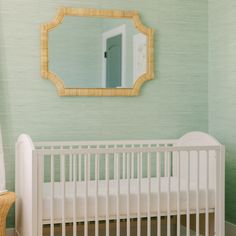 a white crib with a mirror on the wall