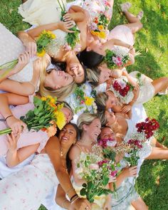 a group of bridesmaids pose for a photo in the grass with their bouquets