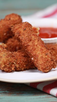 some fried food on a white plate with ketchup and sauce in the background