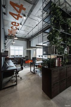 an office with plants and desks in the middle of it, surrounded by glass partitions