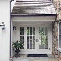 an image of a white front door with two glass doors and potted plants on the side