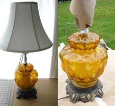 a lamp that is on top of a table next to a glass vase with a bird on it